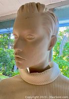 Close-up of mannequin head showing facial features and hair detail outdoors.