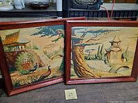 Both framed paintings side by side on a surface, showing overall size and style.