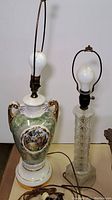 Photo showing two vintage lamps: a ceramic Victorian style lamp and a pressed glass base lamp, bulbs installed, no shades.