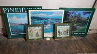 Full view of all six golf-themed prints and posters displayed on wooden floor leaning against a wall