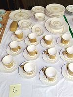 Full set including plates, bowls, cups, saucers, serving platters and butter dish on a white cloth backdrop