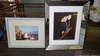 Framed art print of tulips in a mirrored frame and framed photo of boats in harbor on a surface