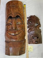 Both wooden masks together with measuring tape for scale, showing size comparison and overall condition.