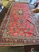 Full view of red Persian medallion rug laid on floor.