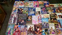An overview photo showing approximately 40 vintage paperback romance novels with colorful and classic romance cover illustrations from the 1960s and 1970s.