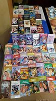 Four rows of vintage romance paperback books laid out face up on a flat surface, showing colorful illustrated covers typical of 1960s and 70s romance novels.