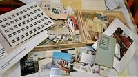 Overview of trays holding vintage stamps, loose stamps, postcards, and ephemera spread on a table.