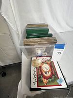 Multiple boxed and loose Christmas cards on a table inside a clear plastic bin and on surface. Cards include Hallmark boxed cards and other various boxes and loose cards.