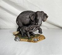 Front view of the porcelain Asian elephants mother and calf figurine standing on a naturalistic base.