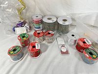 Craft ribbons and a small Santa ornament arranged on a white background showing various ribbon colors, sizes, and patterns