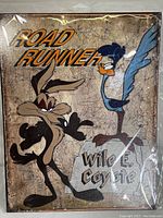 Front view of the metal tin sign showing Road Runner and Wile E. Coyote with text.