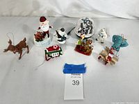 All nine vintage Christmas ornaments grouped on white cloth background. Items include Rudolph, Santa, snowman, tram, reindeer, snow globe, Scooby-Doo and Shaggy, Yeti, sled with mouse and elephant head.