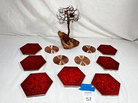 Photo showing entire lot including the wire bonsai tree sculpture mounted on stone and surrounding decorative red and copper coasters.