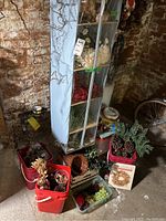 Overall lot of arts and crafts supplies arranged on basement floor and shelf organizer, showing multiple baskets with natural and artificial foliage, pine cones, wreath frames, and storage.