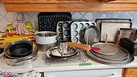 Wide view of all baking pans, trays, a rolling pin, and plastic freezer bags arranged on countertop.