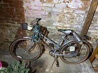 Full side view of Supercycle Commuter Six women's bicycle in worn condition, with power brakes, mudguards, rear rack, coiled lock, and air pump visible.