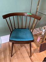 Front view of vintage wood chair with curved back and blue cushion.