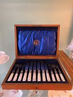 Open mahogany presentation case lined with blue satin and velvet showing all pieces