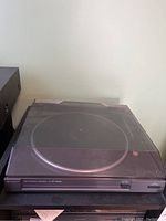 Turntable with closed dust cover, showing the unit's exterior and power/speed controls.