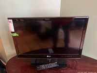 Front view of LG 26 inch TV on table with remote placed in front.
