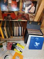 Shelf display of various LP albums featuring famous artists, records stored in boxes below