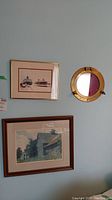 Wall display showing two framed prints and one round porthole mirror, hung together.