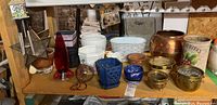 Shelf display of assorted plant pots and decorative items including glass and metal pieces