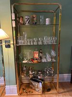 Full front view of brass shelving unit with glass shelves