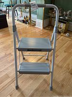 Front view of the Mastercraft metal folding stepstool with two ribbed steps and handlebar.