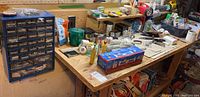 Wide view of wooden table filled with assorted hardware and tools, showing organizer drawers, hand tools and packaged items