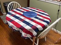 Kitchen table covered with red, white, and blue tablecloth, showing the white spindle back chair with green seat cushion.