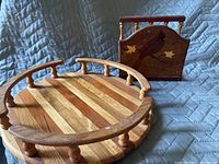 Photo showing a round wooden Lazy Susan with vertical spindled railing and a wooden napkin holder featuring a bird carving and two leaves.