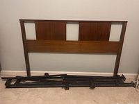 Photo of a full size wooden headboard with rectangular panels and an adjustable metal bed frame.