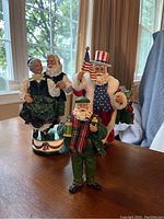 Photo showing all three Santa figures including dancing couple, patriotic Santa, and green dressed Santa with teddy bear.