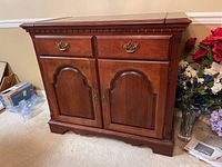Photo of wooden buffet showing front view with extendable side panels partially extended, highlighting drawers, cabinet doors, and surface top.