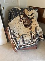 Blanket draped over chair showing angel, stars, and 'PEACE' text with fringed edges
