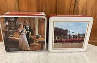 Two vintage English Royalty collectible tins shown side by side on a white marble surface. One depicts a procession outside Buckingham Palace, the other depicts Queen Elizabeth II and Prince Philip indoors.