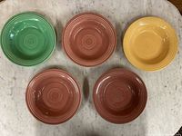 Top view of all five vintage Fiesta bowls in various colors (green, yellow, red) arranged on marble surface.