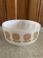 Side view of vintage white milk glass bowl showing brown sunflower floral pattern repeated around the outside