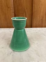 Side view of green glazed ceramic egg cup showing the conical shape and glossy finish.