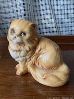Full side view of the seated ceramic cat figurine showing detailed fur texture and coloration.