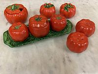 Overview of the tomato shaped dish set including all pieces on a countertop.
