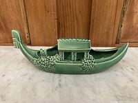Side view of the green ceramic gondola planter showing the detailed floral design and cabin covering