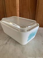 Side angle showing overall dish with clear ribbed lid and turquoise Amish 502 pattern