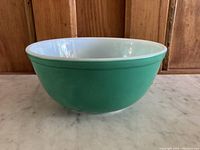 Side view of the vintage Pyrex mixing bowl showing green exterior with white interior.