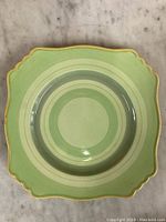 Top view of vintage Royal Winton green and cream decorative plate with scalloped edges and gold trim.