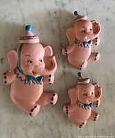 Set of three pink chalkware elephants arranged with one large and two smaller elephants
