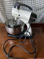 Full view of the vintage Sunbeam Mixmaster electric stand mixer with two stainless steel mixing bowls on wooden surface.