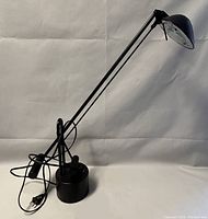 Photo of the black metal cantilever desk lamp in off state showing adjustable arms, weighted circular base, and dome shade.