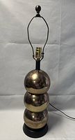 Full view of the lamp without bulb showing stacked triple ball chrome gold spheres on a black base.